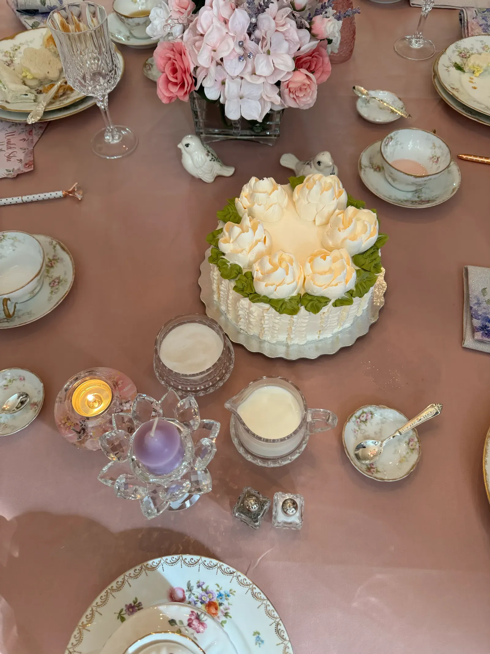 White floral gluten-free celebration cake on a tea table set with vintage china and pink blooms